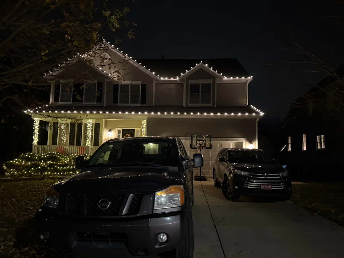 Warm white roofline lights across the gables, dormers and porch columns of a two-story home at night