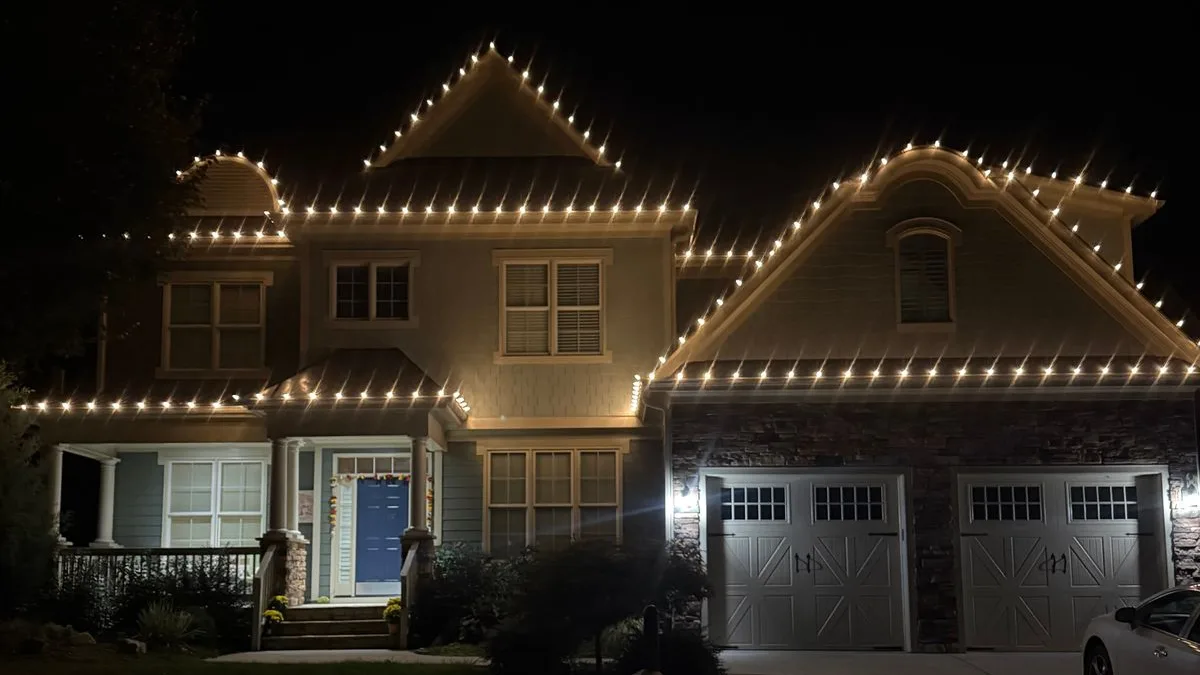 Warm white C9 lights along every peak of a two-story home with a blue front door in Wake Forest, NC