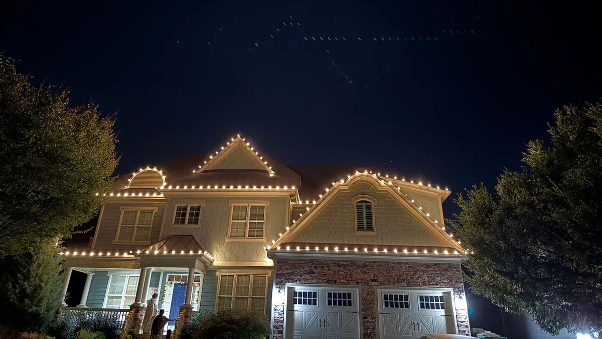 Warm white roofline lighting on a two-story home with a copper porch roof in Wake Forest, NC