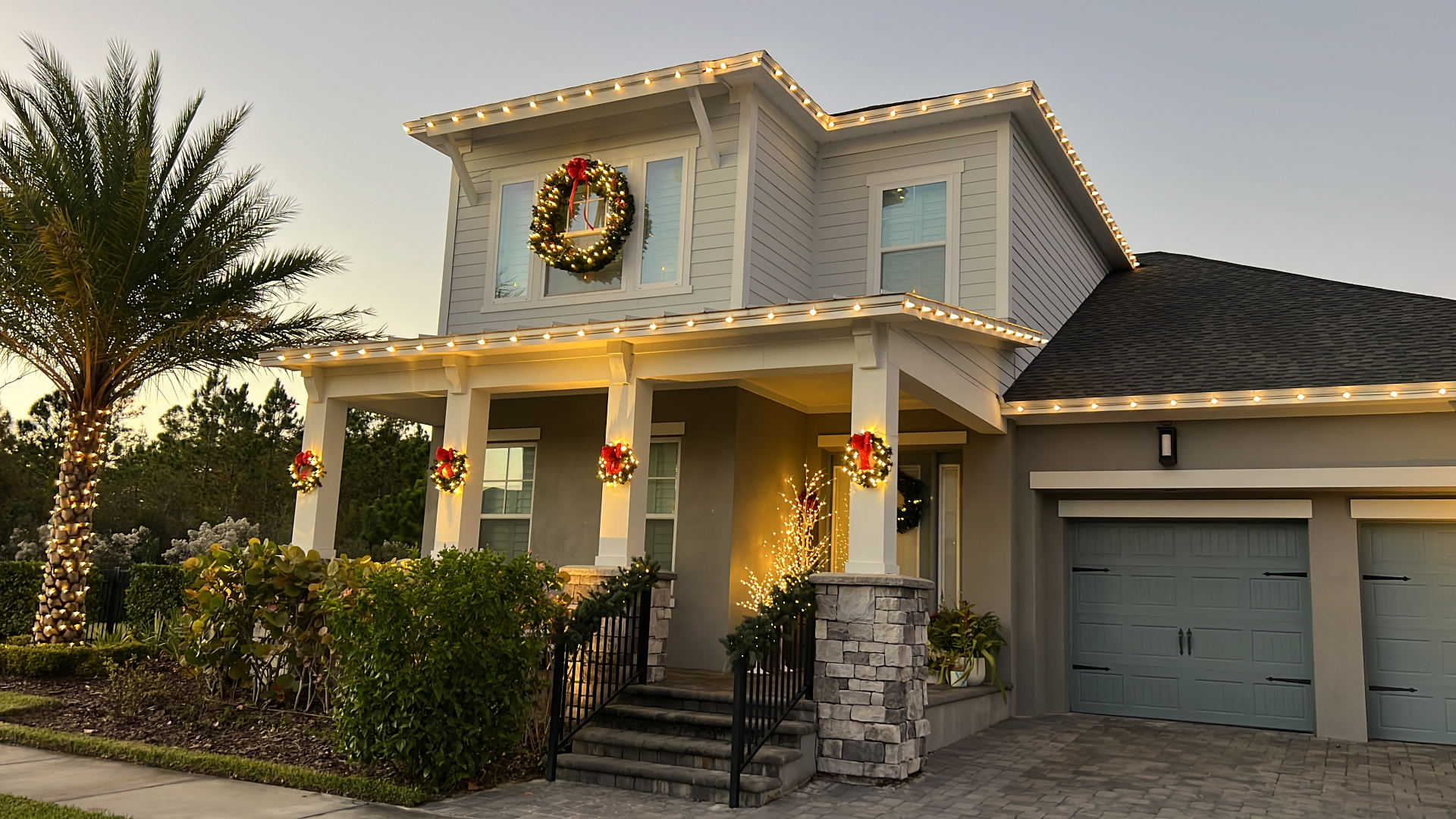 Professional Christmas light installation with elegant wreaths and warm roofline lights
