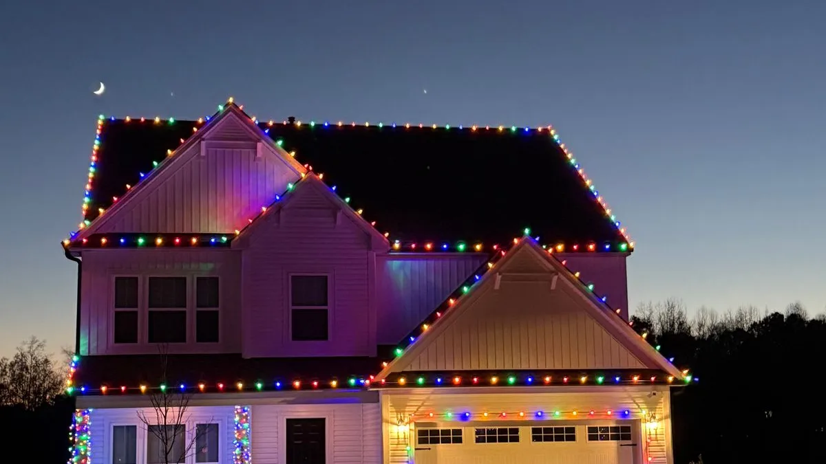 Multicolor Christmas light installation on a two-story home with wrapped columns in Wake Forest, NC