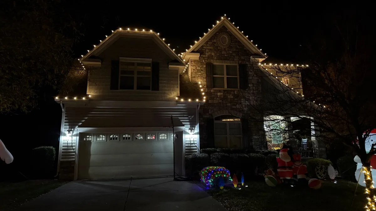 Roofline Christmas lights on a stone and siding two-story home in Wake Forest, NC
